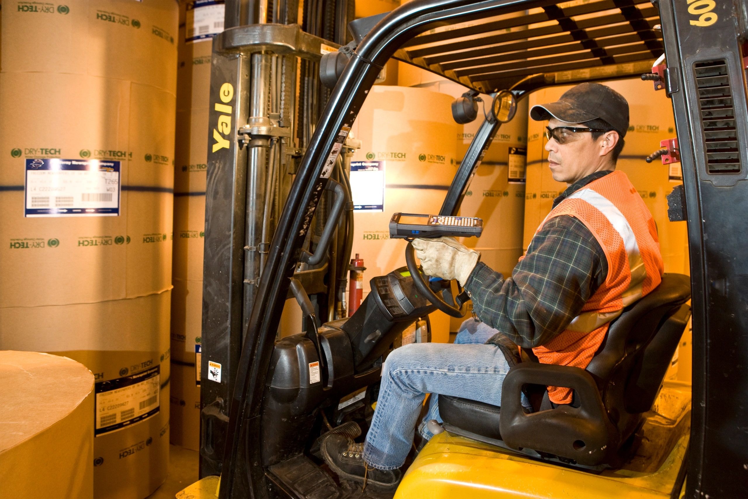 Warehouse forklift worker in orange safety vest