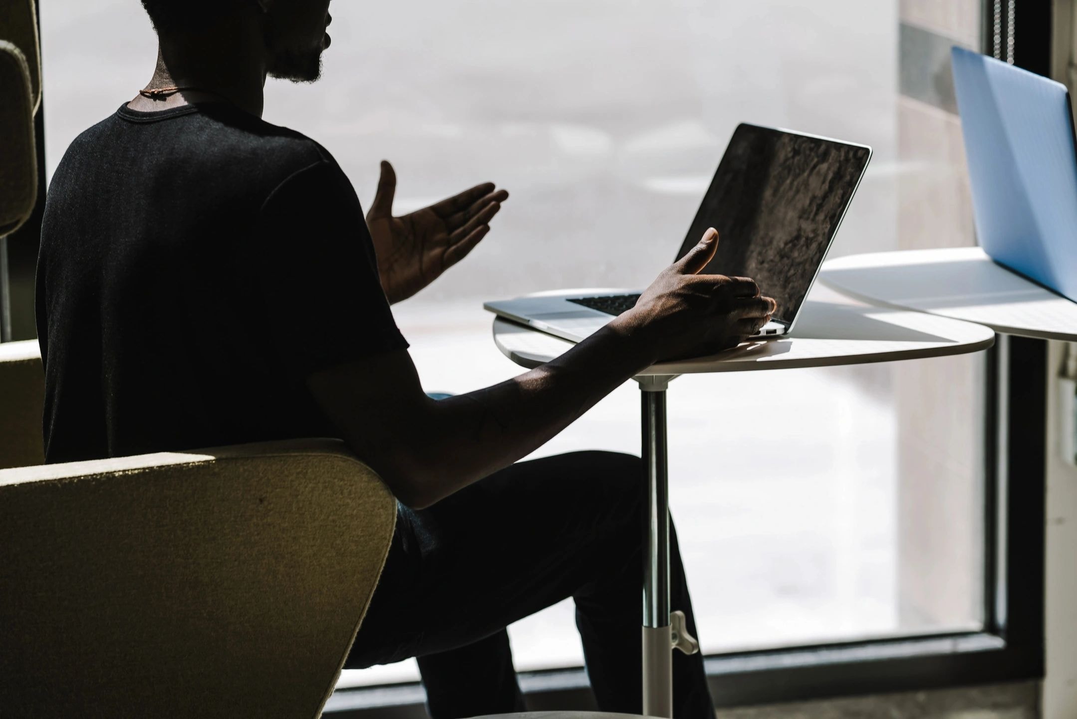 Person silhouetted at laptop desk working